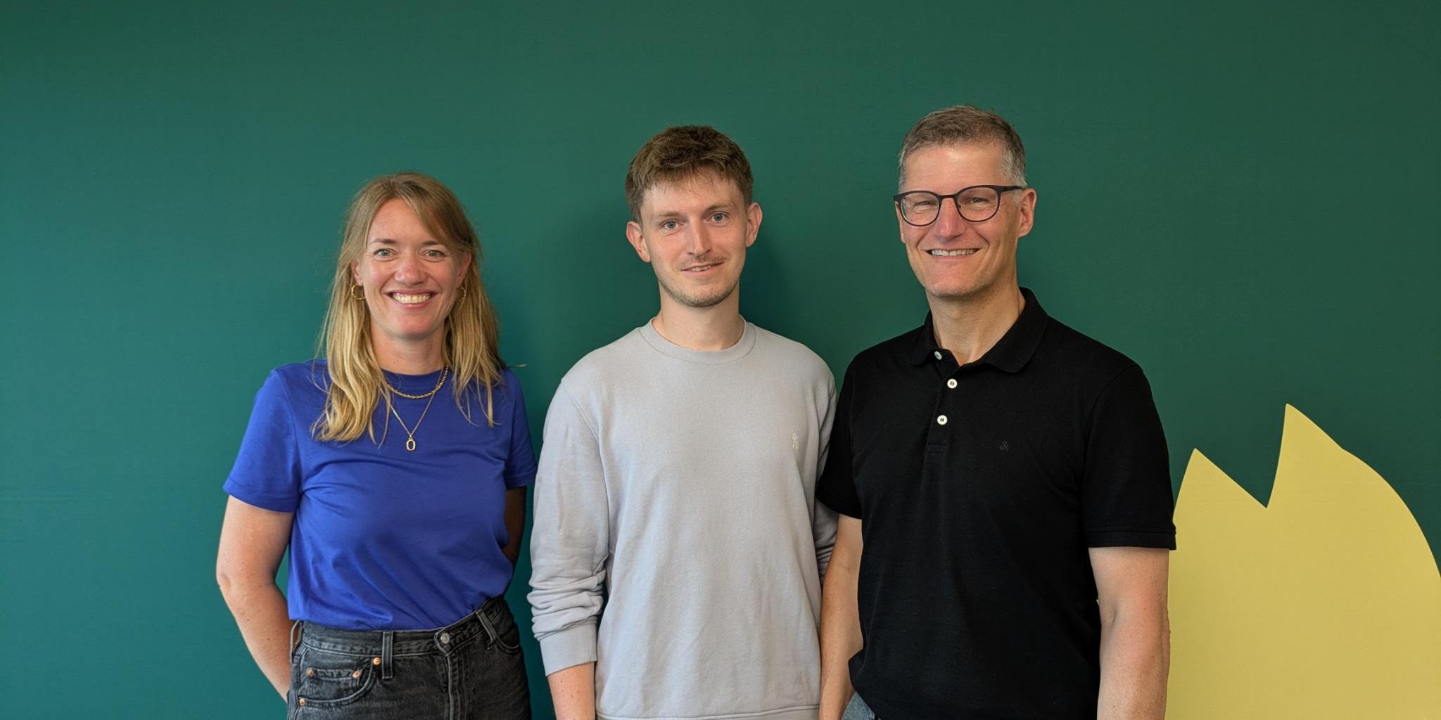 Familienfördergarantie Katharina Könning, Leon Herbstmann und Tilman Fuchs vor einer Grünen Pressewand
